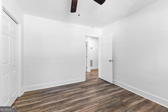 unfurnished bedroom with baseboards, visible vents, dark wood-style floors, and a closet