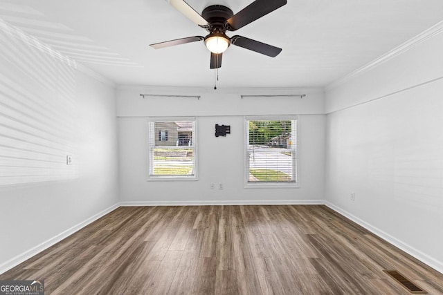empty room featuring wood finished floors, visible vents, crown molding, and ceiling fan