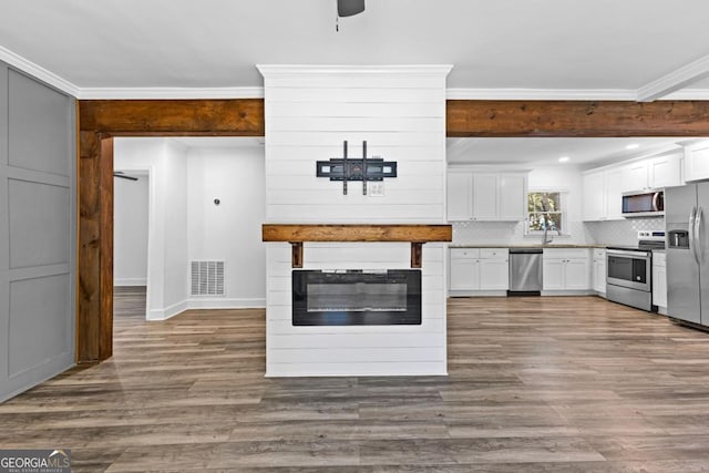 kitchen featuring tasteful backsplash, appliances with stainless steel finishes, white cabinetry, dark wood-type flooring, and visible vents