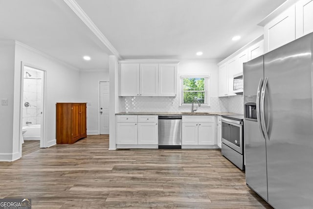 kitchen with crown molding, tasteful backsplash, a sink, stainless steel appliances, and white cabinets