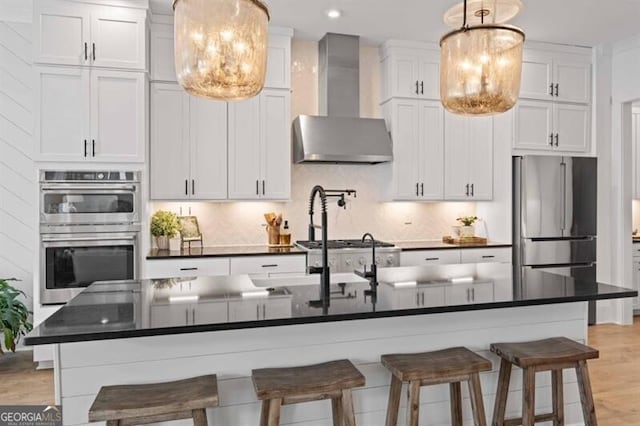 kitchen with wall chimney range hood, dark countertops, tasteful backsplash, and stainless steel appliances