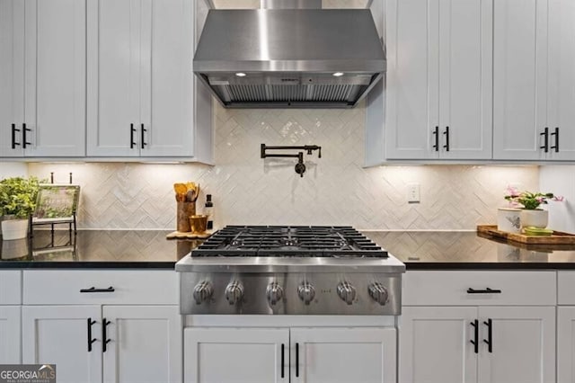kitchen with backsplash, dark countertops, wall chimney range hood, and stainless steel gas cooktop