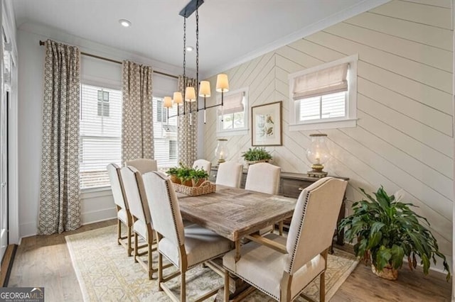 dining space with light wood-style floors, a healthy amount of sunlight, crown molding, and an inviting chandelier