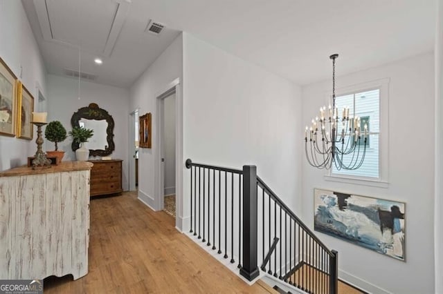 hallway with attic access, light wood-type flooring, visible vents, recessed lighting, and an upstairs landing