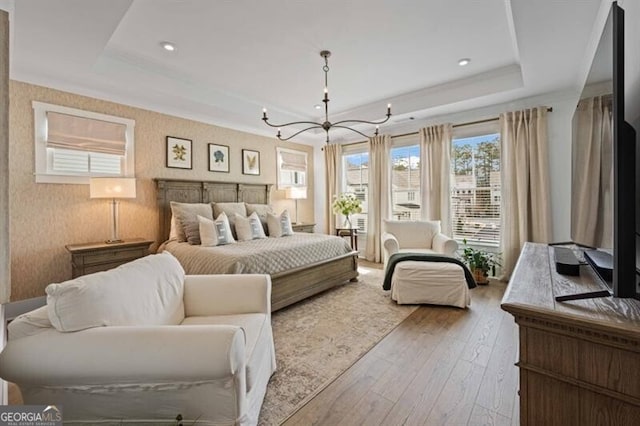 bedroom featuring a tray ceiling, a chandelier, and wood-type flooring