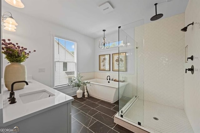 full bathroom featuring a freestanding bath, marble finish floor, tiled shower, and a sink