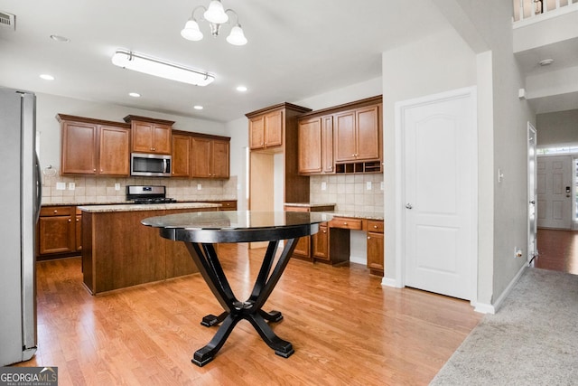 1502 Silver Mist Cir, Powder Springs, GA 30127 - kitchen with light wood finished floors, backsplash, brown cabinets, and appliances with stainless steel finishes