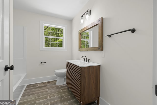 1271 Hayes St, Madison, GA 30650 - bathroom with toilet, a washtub, vanity, baseboards, and wood finish floors