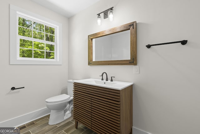 1271 Hayes St, Madison, GA 30650 - half bath with visible vents, toilet, vanity, baseboards, and wood finish floors