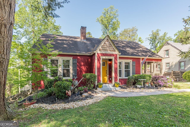 view of front of home with a chimney, a front lawn, and roof with shingles