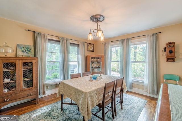 dining space with an inviting chandelier, wood finished floors, and baseboards