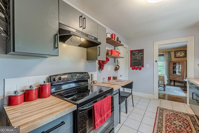 kitchen with wooden counters, under cabinet range hood, open shelves, light tile patterned floors, and black range with electric cooktop
