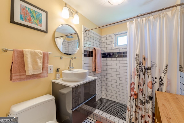 bathroom with vanity, toilet, and tiled shower