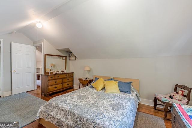 bedroom with lofted ceiling, wood finished floors, and baseboards