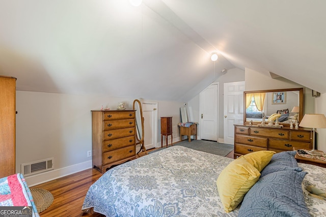 bedroom featuring lofted ceiling, baseboards, wood finished floors, and visible vents