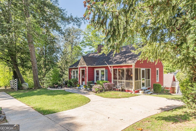 view of front of house with a chimney, a front lawn, and a shingled roof
