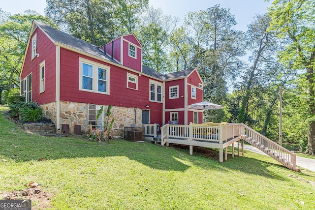 back of property featuring a lawn, a shingled roof, and a deck