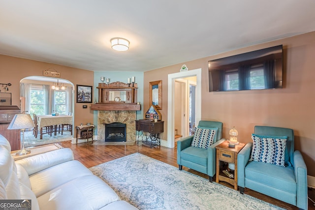 living area with arched walkways, wood finished floors, and baseboards