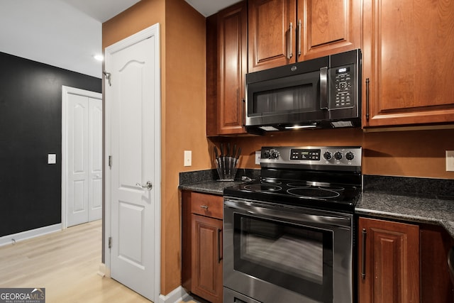 195 14th St Unit 1403, Atlanta, GA 30309 - kitchen featuring black microwave, stainless steel electric range oven, light wood-type flooring, brown cabinets, and dark stone counters