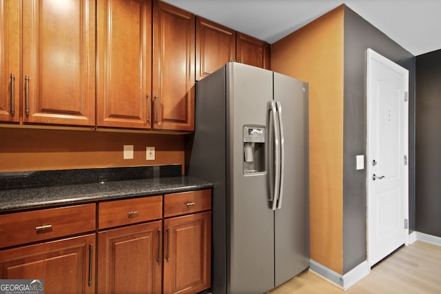 195 14th St Unit 1403, Atlanta, GA 30309 - kitchen with stainless steel fridge, light wood-style floors, brown cabinets, and dark stone countertops