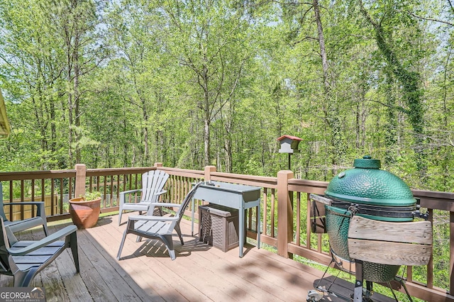 wooden terrace with area for grilling and a wooded view