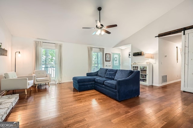 living room featuring visible vents, a barn door, ceiling fan, and hardwood / wood-style floors