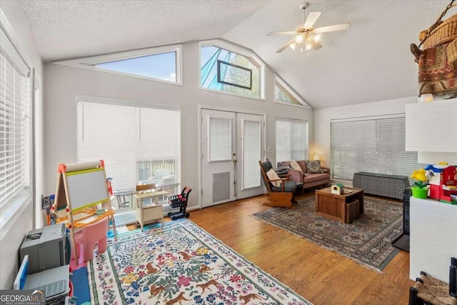 interior space featuring vaulted ceiling, a ceiling fan, wood finished floors, and a textured ceiling