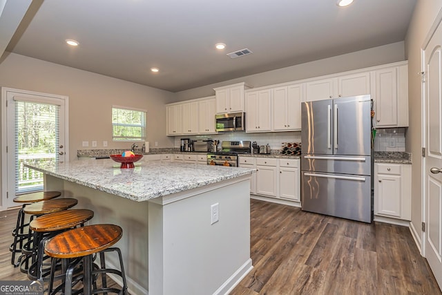 kitchen featuring dark wood-style flooring, tasteful backsplash, appliances with stainless steel finishes, white cabinetry, and visible vents