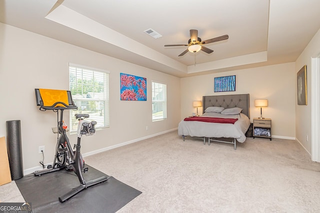 carpeted bedroom with a tray ceiling, visible vents, a ceiling fan, and baseboards