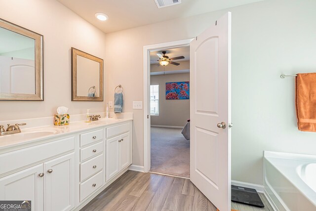 full bathroom with a ceiling fan, wood finished floors, a sink, and double vanity