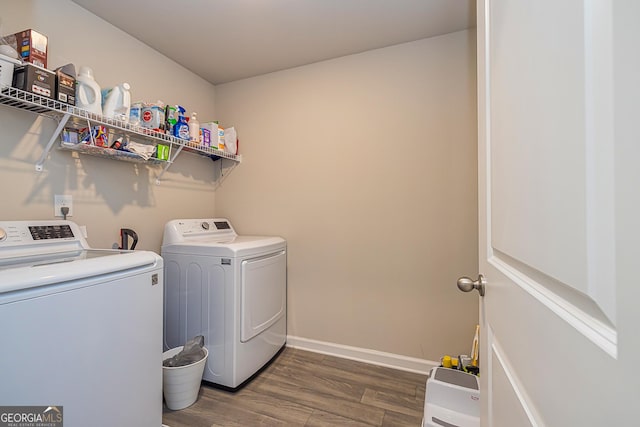 clothes washing area featuring washing machine and clothes dryer, baseboards, dark wood-style flooring, and laundry area