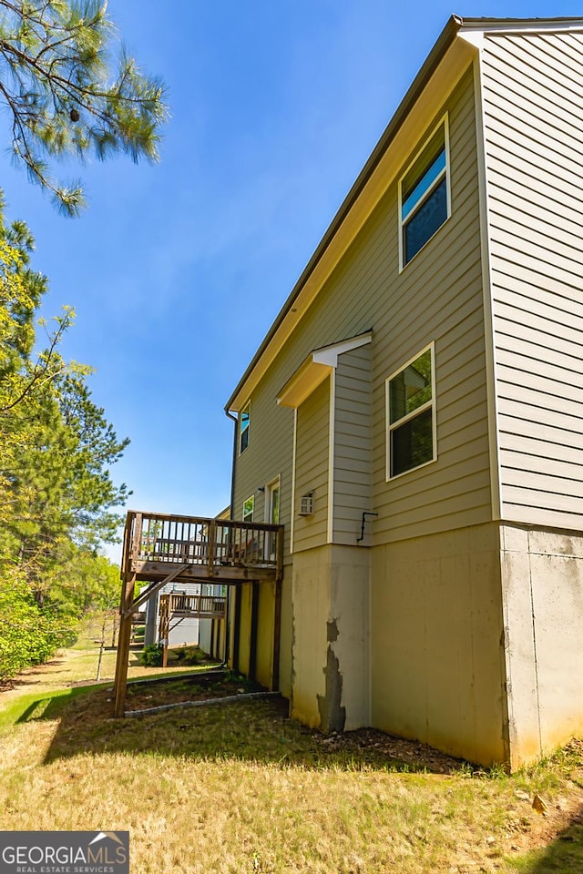 back of property featuring a wooden deck and a lawn