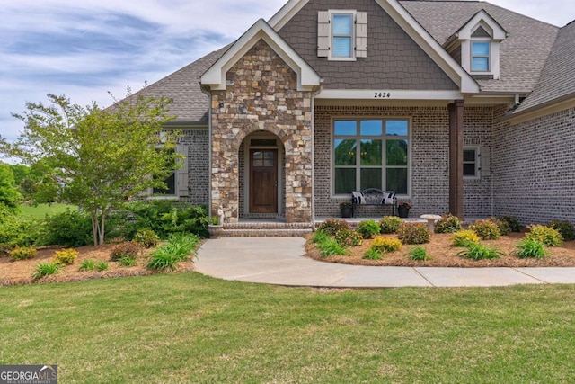 2424 Princeton Bend Way, Bogart, GA 30622 - craftsman-style home with a front yard, stone siding, a shingled roof, brick siding, and covered porch