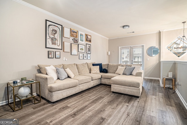 living room featuring wood finished floors, visible vents, ornamental molding, baseboards, and a chandelier