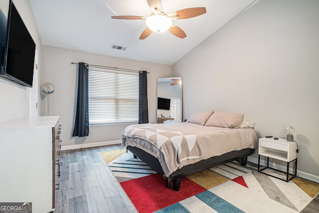 bedroom featuring wood finished floors, visible vents, lofted ceiling, and baseboards