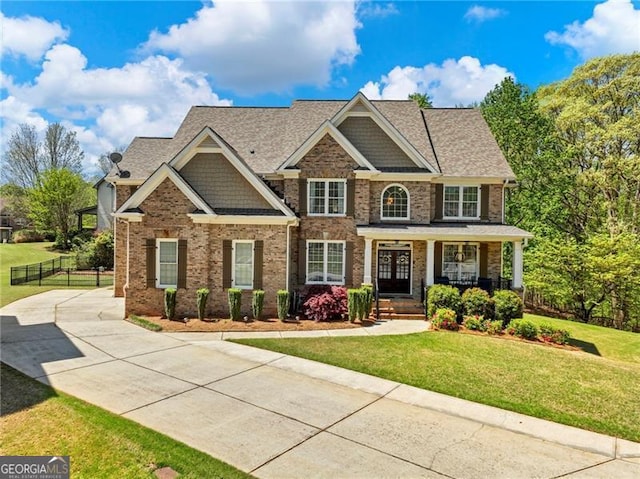 craftsman-style house with brick siding, fence, a front yard, and covered porch