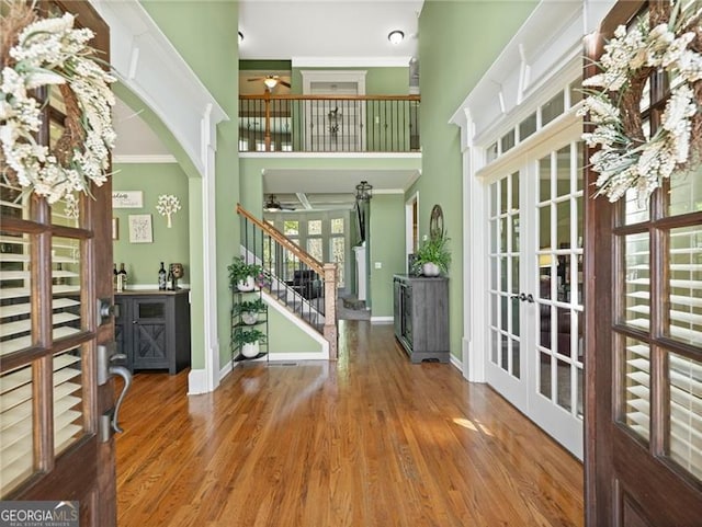 foyer entrance with plenty of natural light, wood finished floors, stairs, ceiling fan, and ornamental molding