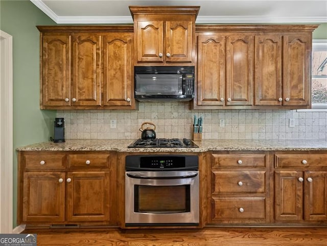 kitchen featuring black appliances, backsplash, light stone countertops, and brown cabinets