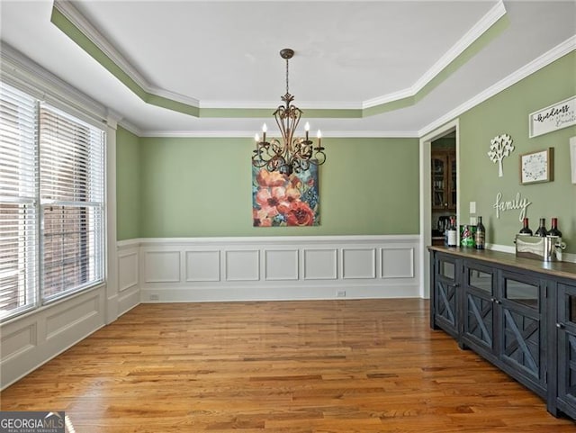 unfurnished dining area featuring a raised ceiling, a healthy amount of sunlight, and an inviting chandelier