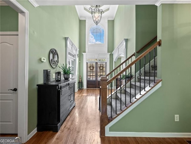 foyer entrance with baseboards, wood finished floors, stairs, and ornamental molding
