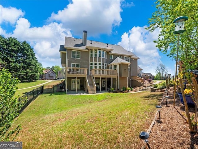 back of house featuring a chimney, stairs, a fenced backyard, a yard, and a deck