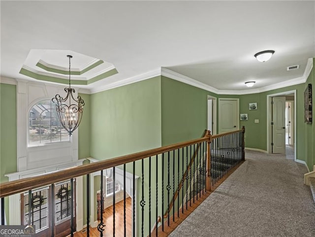 hallway featuring baseboards, visible vents, an upstairs landing, a chandelier, and ornamental molding