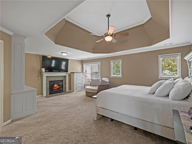 bedroom featuring carpet floors, ornamental molding, a tray ceiling, and a fireplace