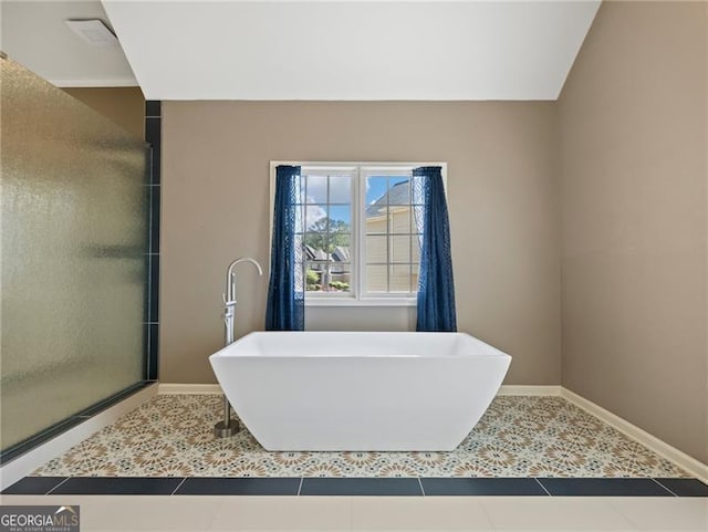 bathroom with a shower stall, baseboards, a soaking tub, and tile patterned floors