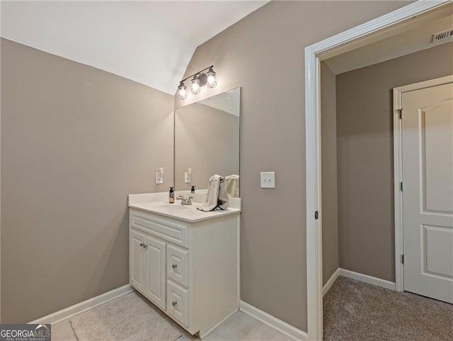 bathroom with vaulted ceiling, vanity, visible vents, and baseboards