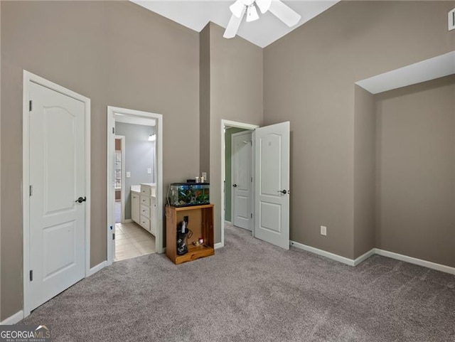 unfurnished bedroom with baseboards, carpet, ensuite bath, and high vaulted ceiling