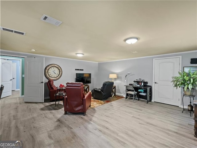 living area with light wood-type flooring, visible vents, baseboards, and ornamental molding