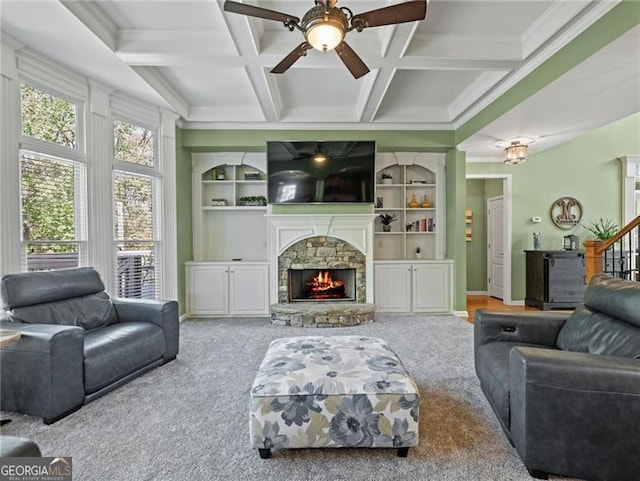 carpeted living room featuring a ceiling fan, a fireplace, coffered ceiling, and ornamental molding