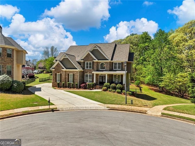 craftsman inspired home featuring brick siding, driveway, a front yard, and fence