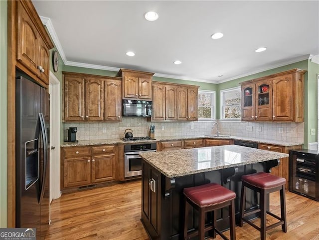 kitchen featuring black appliances, ornamental molding, and a sink